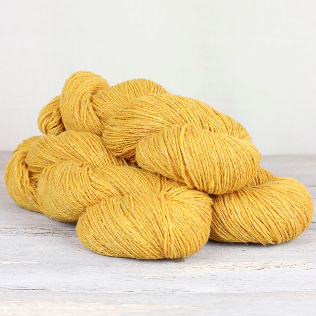 Three skeins of bright yellow Fibre Co. Arranmore Light yarn.