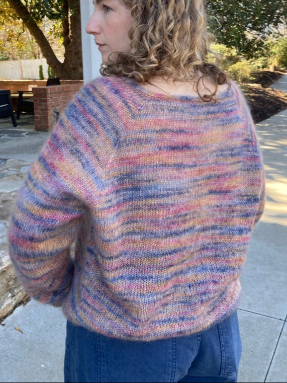 Person wearing a colorful sweater standing outdoors on a stone path.