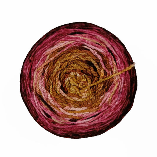 Ball of gradient Malabrigo Metamorphosis Sock yarn in burgundy and caramel shades.
