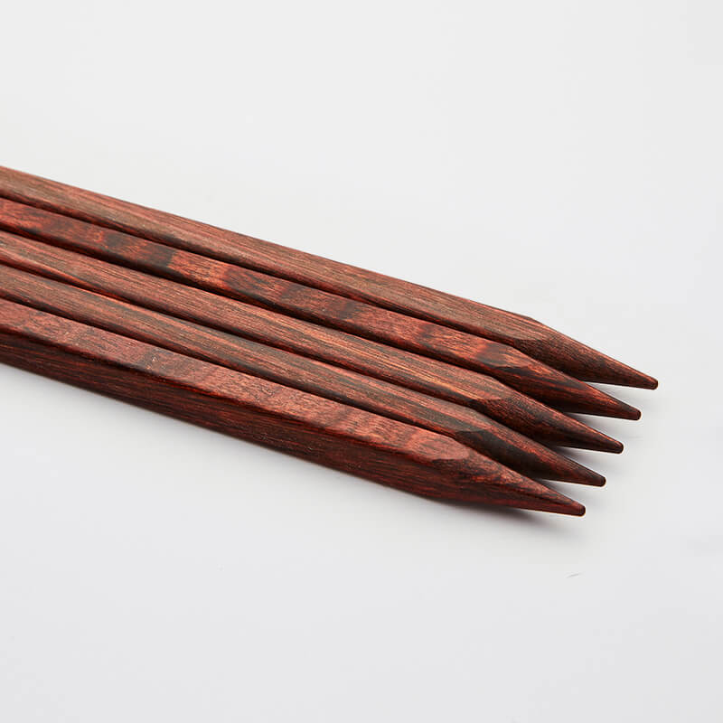 Close up on set of 5 brown cubics double pointed needles.
