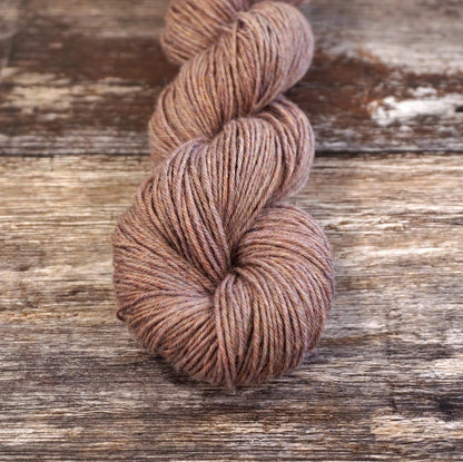 Light brown skein of CoopKnits Socks Yeah! yarn on a wooden surface. 