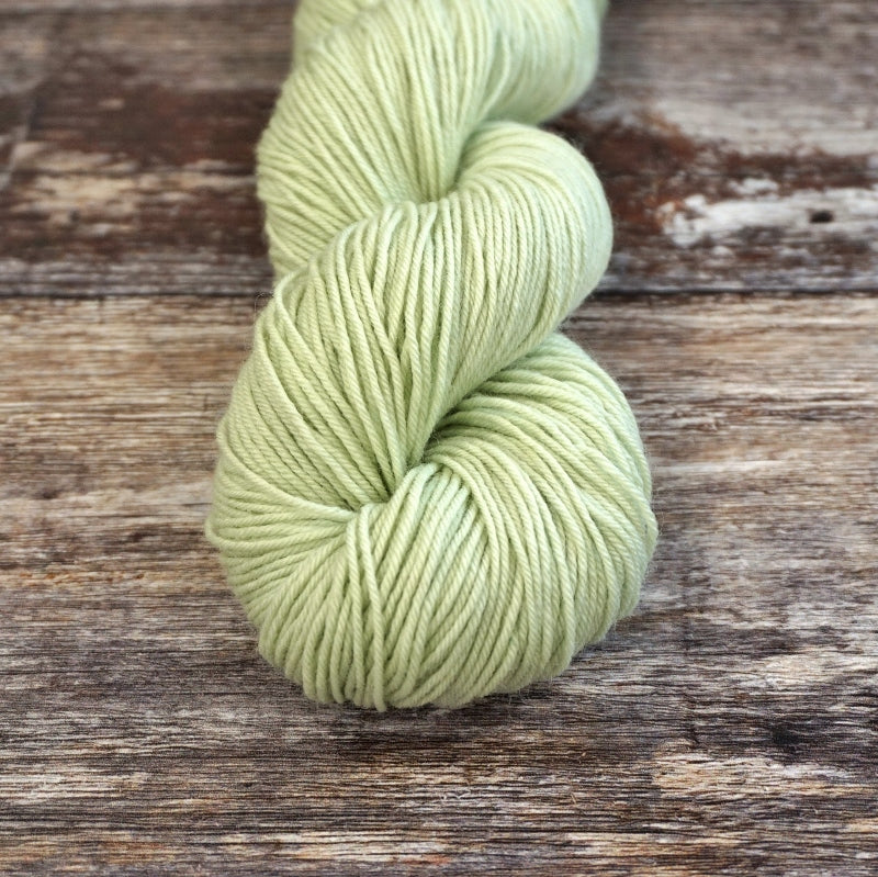 Mint green skein of CoopKnits Socks Yeah! yarn on a wooden surface. 