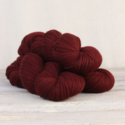 3 skeins of dark red Fibre Co. Amble yarn. 