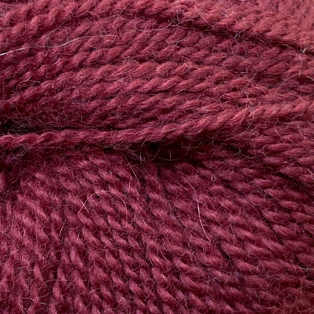 Close up on a ball of burgundy Jo Sharp Alpaca Kid Lustre yarn. 