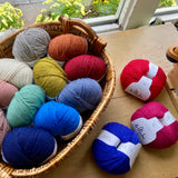 Basket of colorful balls of yarn on a wooden table by a window. 