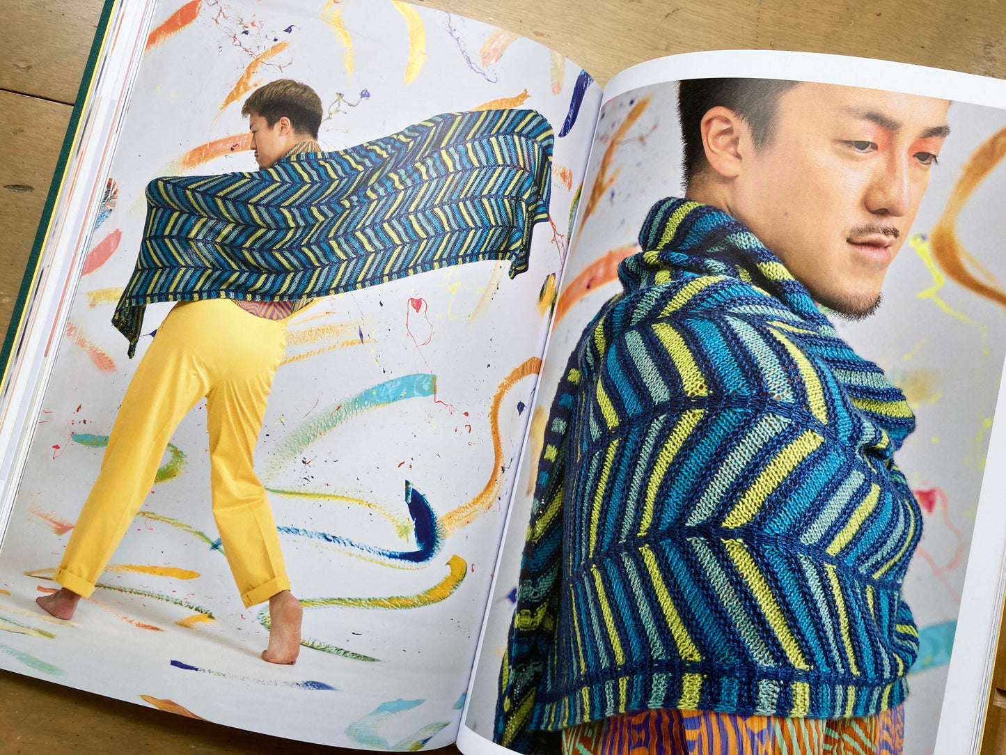 Stephen West’s Painting Shawls book, lying open, showing colorful photos of people modeling shawls. 