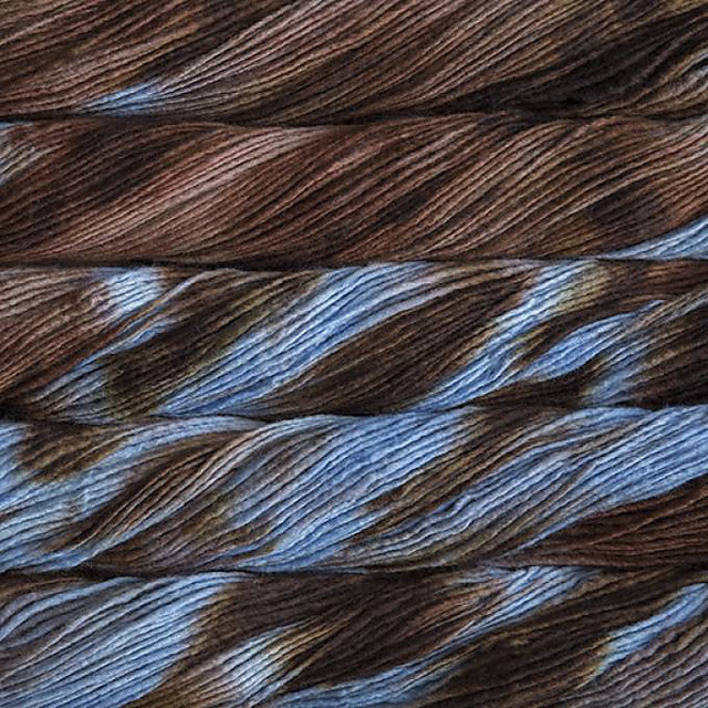 Close up on variegated brown and blue skeins of Malabrigo Lace yarn. 