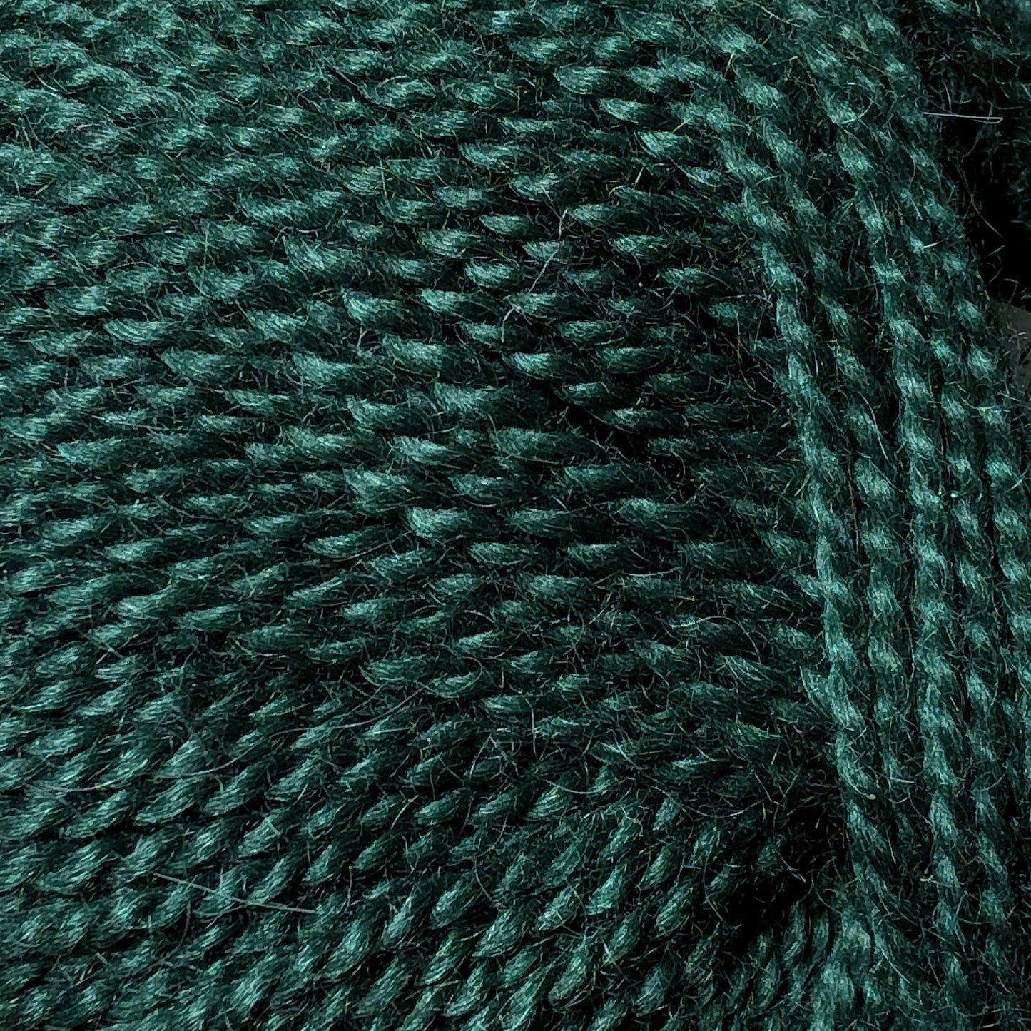 Close up on a ball of forest green Jo Sharp Alpaca Kid Lustre yarn. 