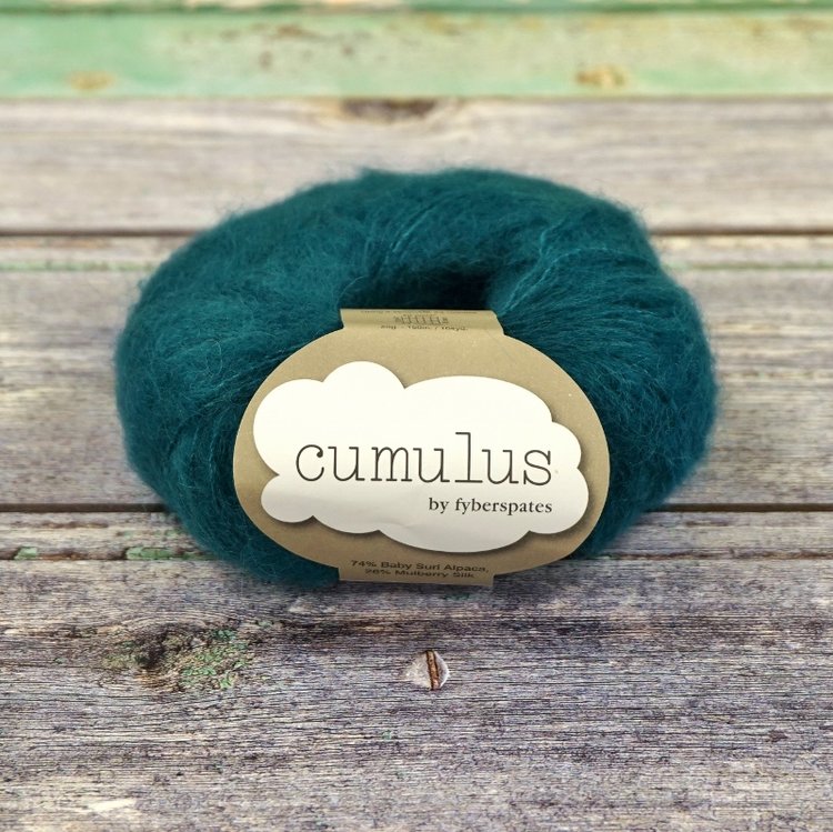 Ball of deep teal Fyberspates Cumulus yarn on a wooden surface. 