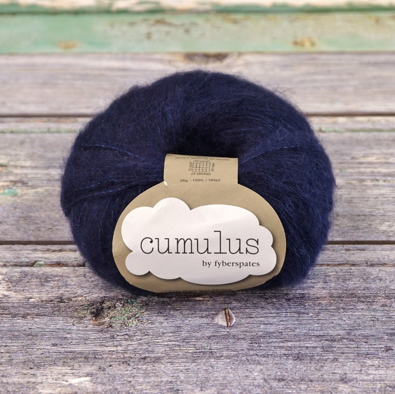 Ball of indigo navy Fyberspates Cumulus yarn on a wooden surface. 