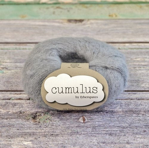 Ball of medium gray Fyberspates Cumulus yarn on a wooden surface. 