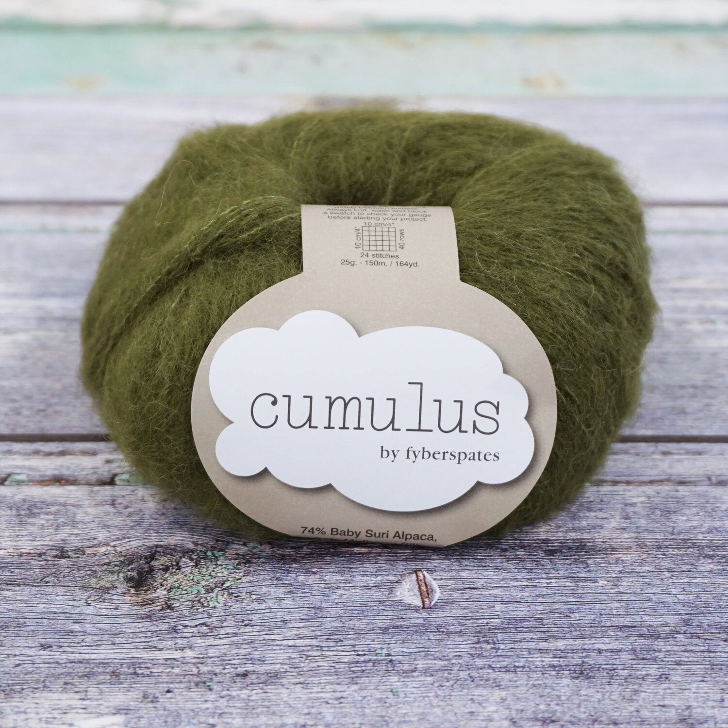 Ball of moss green Fyberspates Cumulus yarn on a wooden surface. 