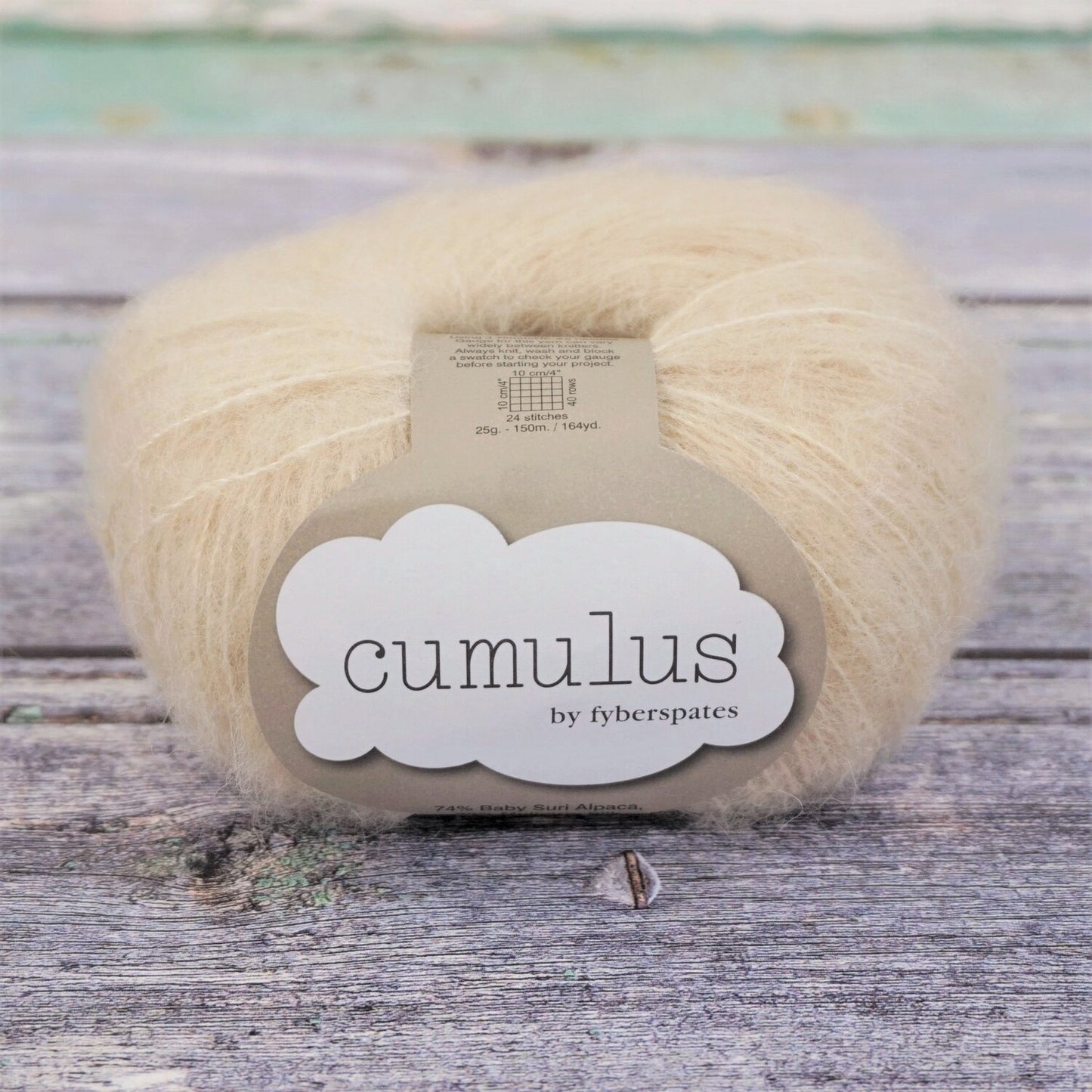 Ball of natural white Fyberspates Cumulus yarn on a wooden surface. 