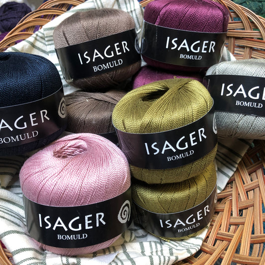 Many colored balls of Isager Bomuld yarn in a fabric lined basket. 