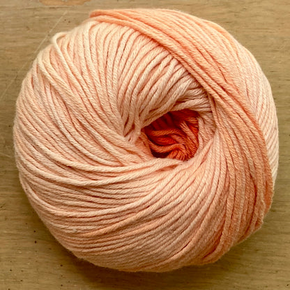 Ball of Katia Degrade yarn in shades of light orange. 
