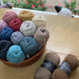 Colorful balls of Isager Highland Wool in a basket on a wooden surface in front of a window - yarn for sale at Hillsborough Yarn Shop, NC, USA