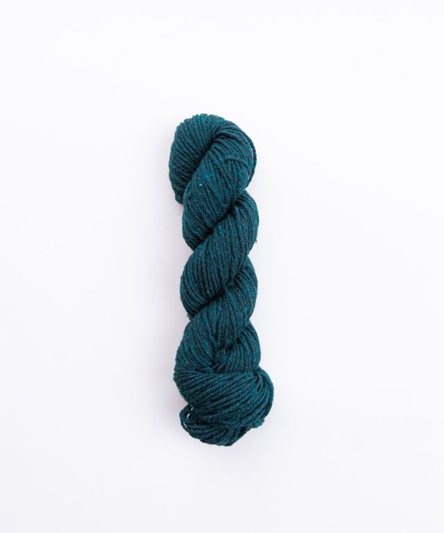 Skein of heathered deep teal Brooklyn Tweed Imbue Worsted yarn. 