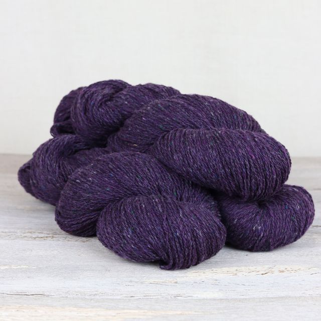 Three skeins of dark purple Fibre Co. Arranmore Light yarn. 