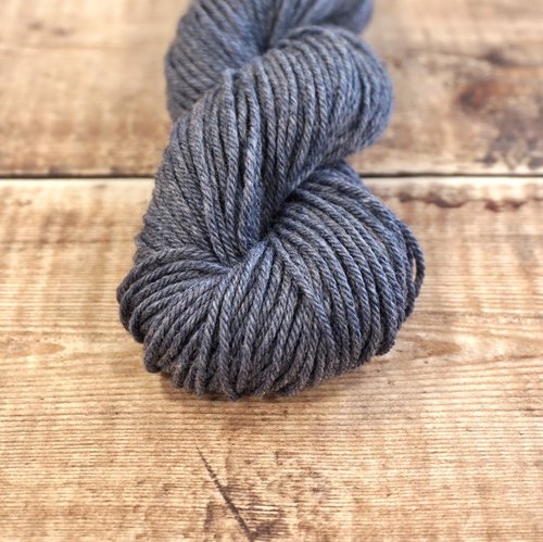 Dark gray skein of CoopKnits Socks Yeah! DK yarn on a wooden surface. 