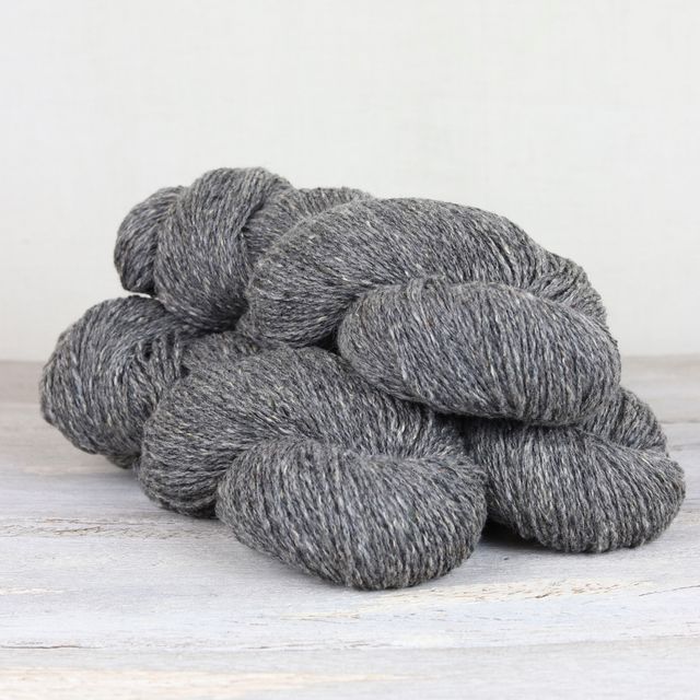 Three skeins of medium gray Fibre Co. Arranmore Light yarn. 