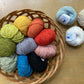 Colorful balls of Elsebeth Lavold Bambouclé in a basket on a wooden surface. 