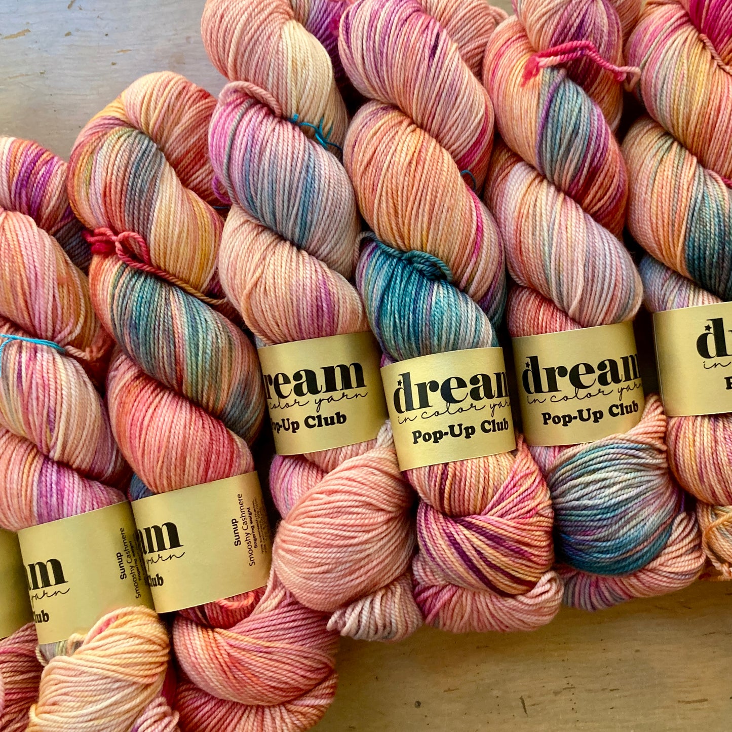 Variegated pink, peach, and blue skeins of Dream in Color Smooshy Cashmere yarn, for sale at Hillsborough Yarn Shop, NC, USA.