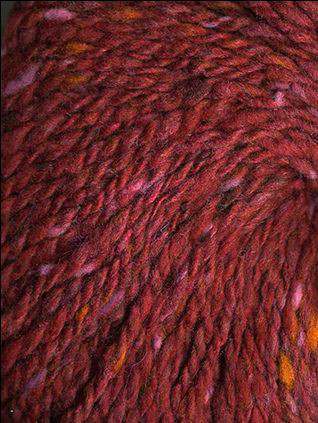 Close up on a dark red tweed ball of Queensland Kathmandu Aran yarn. 