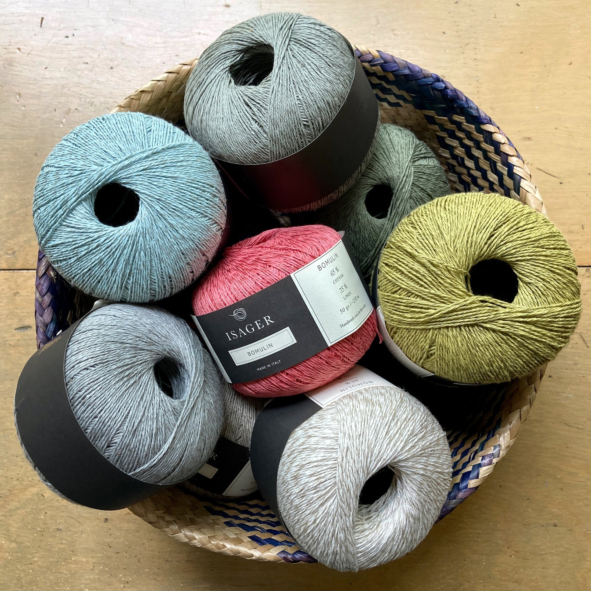 Basket of colorful Isager Bomulin yarn on a wooden surface. 