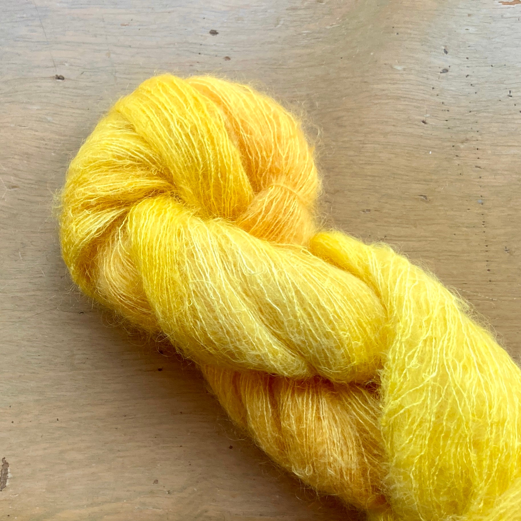 Bright yellow skein of Fleece Artist / Hand Maiden Superkid Silk yarn, colorway Buttercup