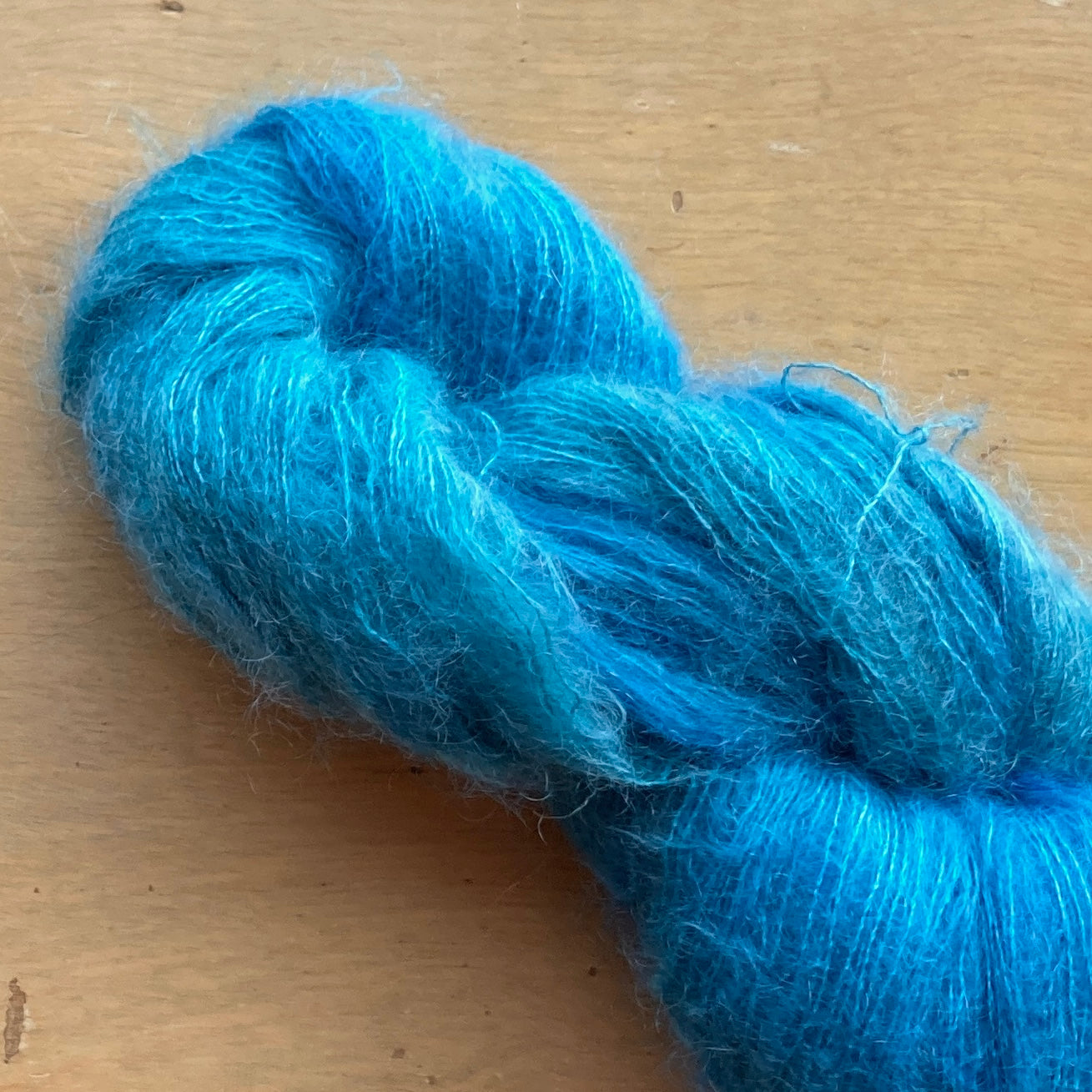 Bright turquoise skein of Fleece Artist / Hand Maiden Superkid Silk yarn, colorway Topaz