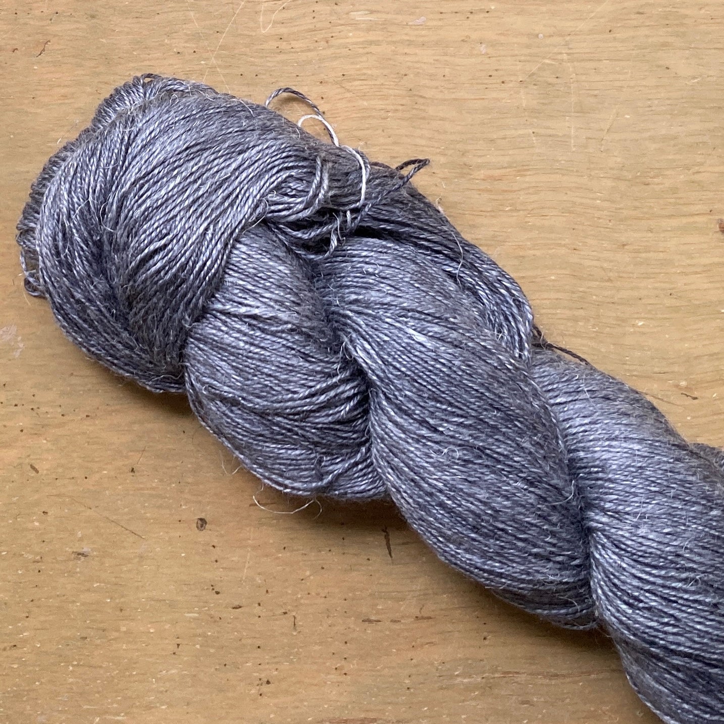 Close up on a medium charcoal gray skein of Hand Maiden Flyss yarn.