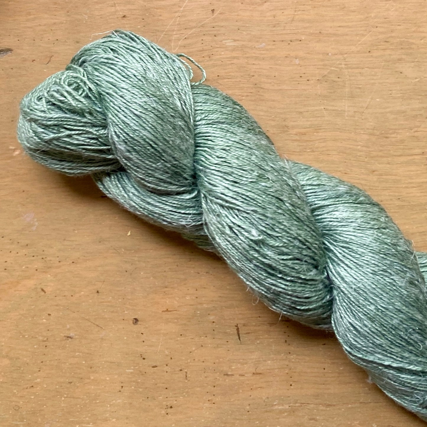 Close up on a Eucalyptus green skein of Hand Maiden Flyss yarn.