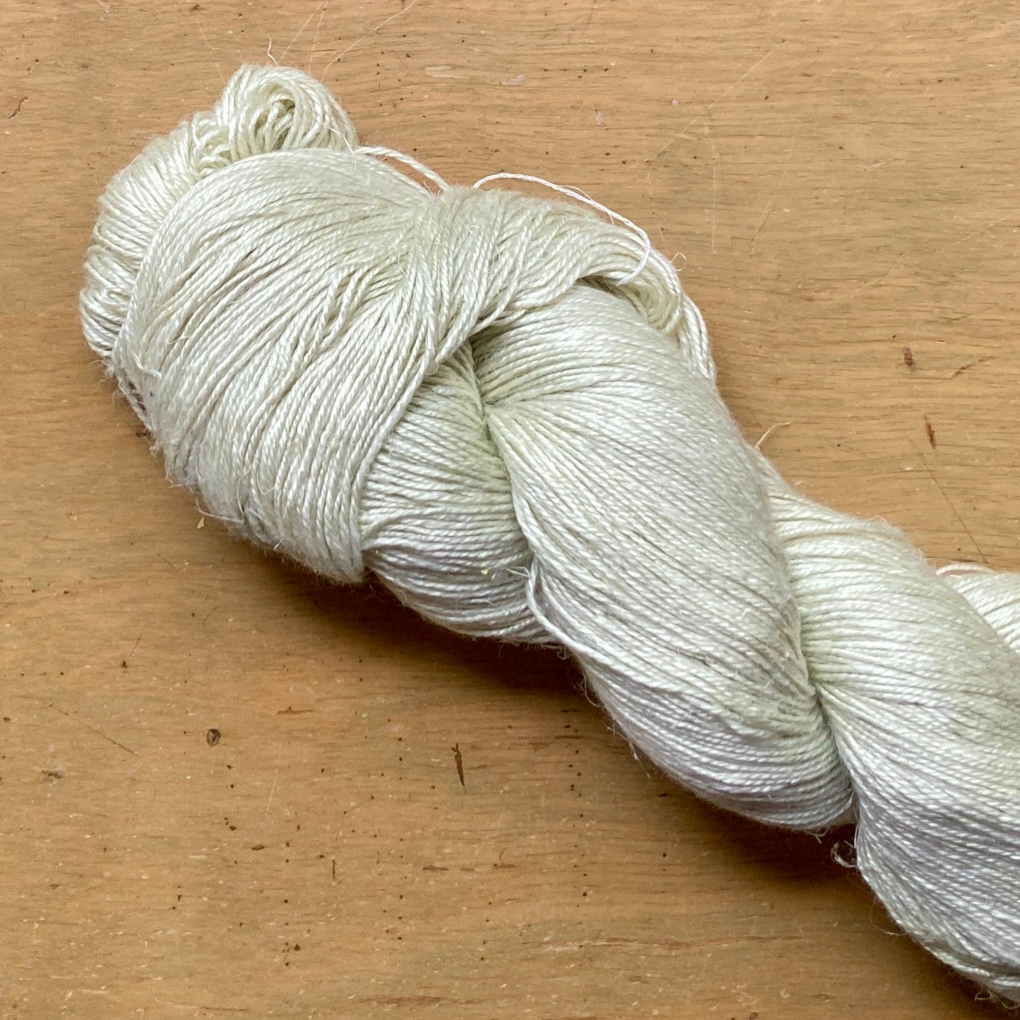 Close up on a pale celery green skein of Hand Maiden Flyss yarn.