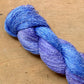 Close up on a variegated blue and purple skein of Hand Maiden Flyss yarn, Periwinkle colorway