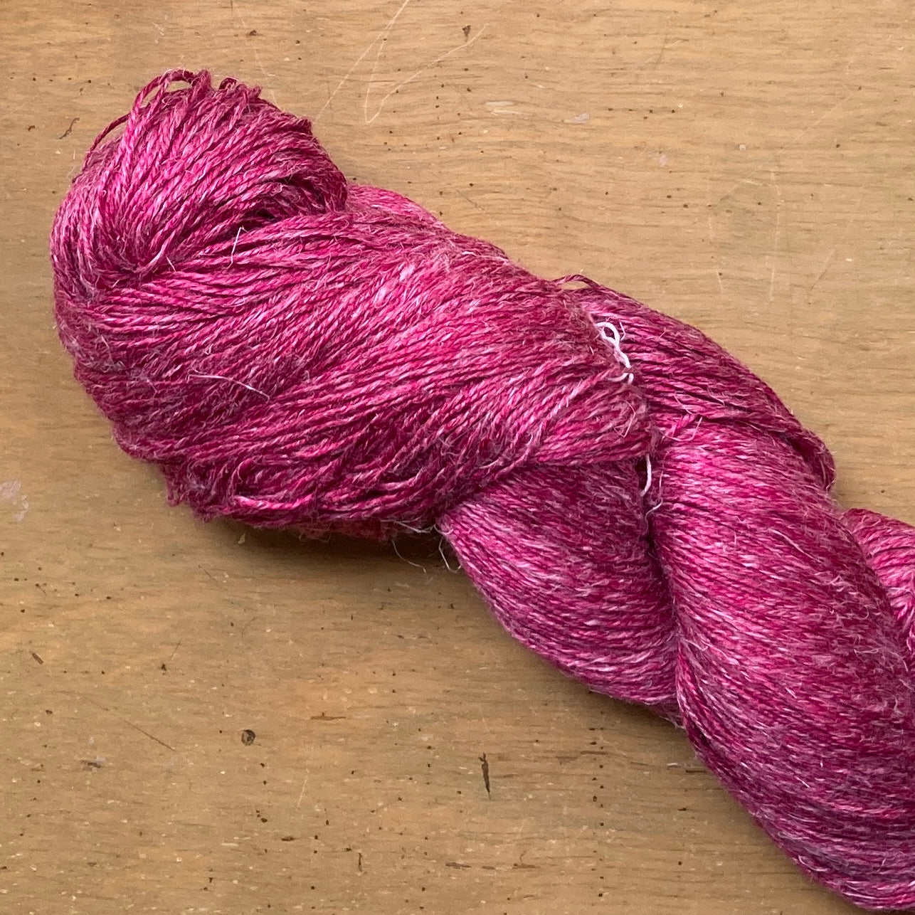 Close up on a raspberry skein of Hand Maiden Flyss yarn.