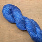 Close up on a medium blue skein of Hand Maiden Flyss yarn, colorway Stellars Jay