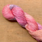 Close up on a pink and coral skein of Hand Maiden Flyss yarn, color Turkish Delight