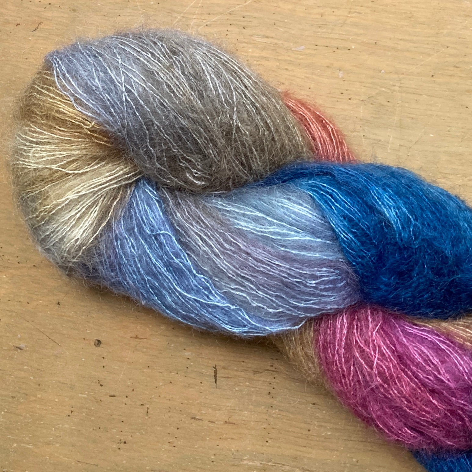 Variegated blue, raspberry, and beige skein of Hand Maiden Superkid Silk yarn, Swan Lake colorway