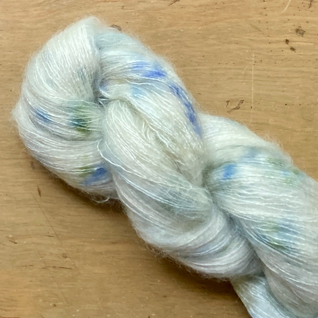 Speckled cream and blue skein of Hand Maiden Superkid Silk yarn. 