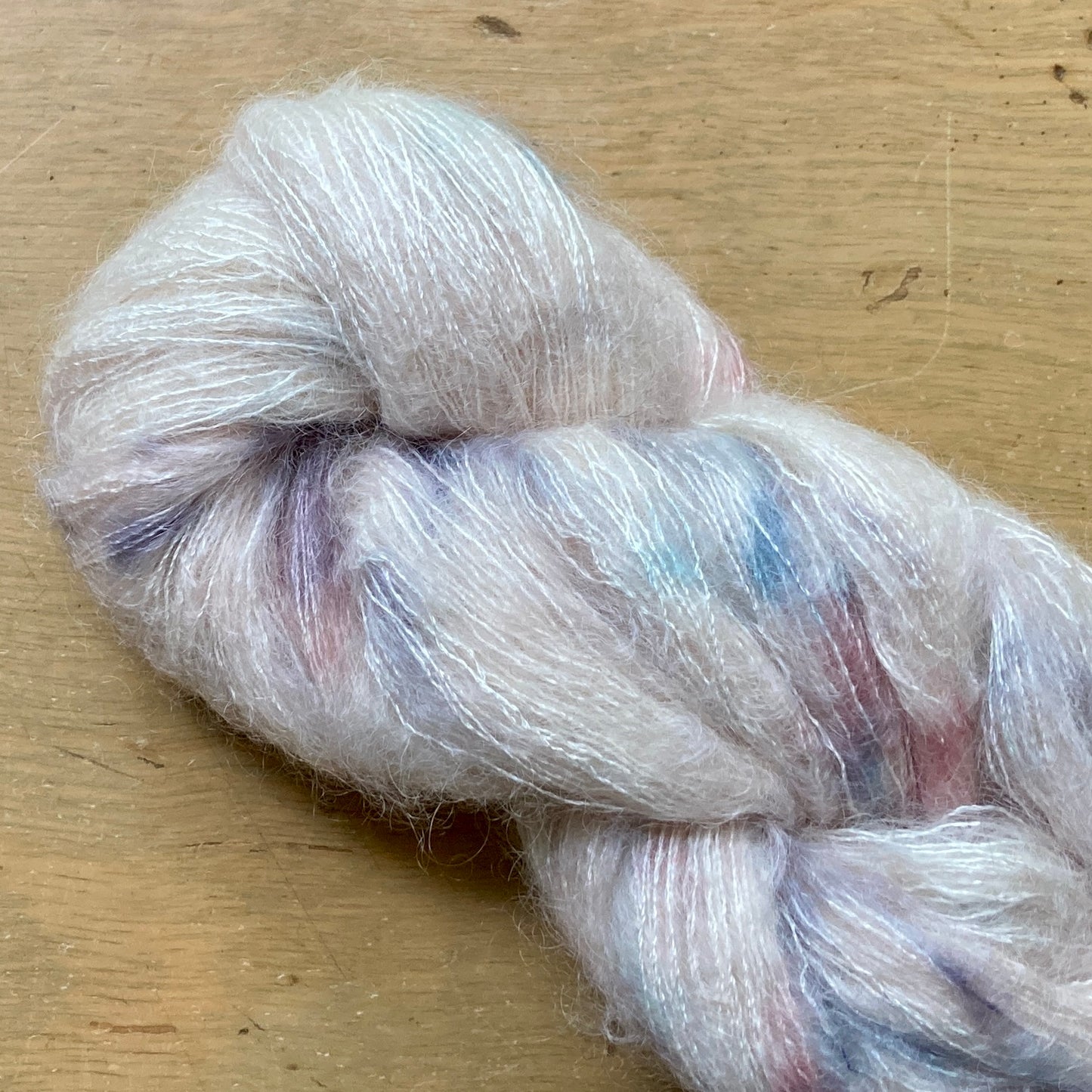 Speckled cream, pink, and blue skein of Hand Maiden Superkid Silk yarn. 