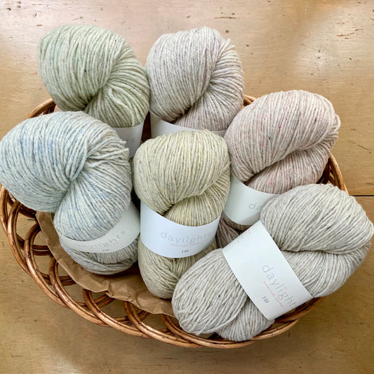 Basket of light-colored Harrisville daylights yarn skeins on a wooden surface