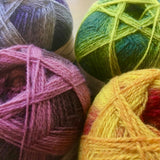 Close up on four colorful balls of self striping Kauni Effektgarn yarn. 