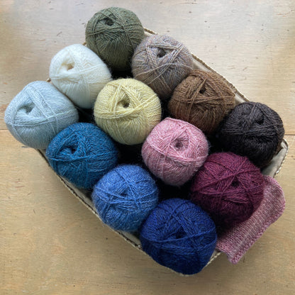 Colorful balls of Isager Highland Wool in a basket on a wooden surface in front of a window - yarn for sale at Hillsborough Yarn Shop, NC, USA