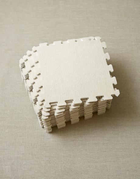 Stack of gray blocking tiles with puzzle piece edges on a beige surface. 