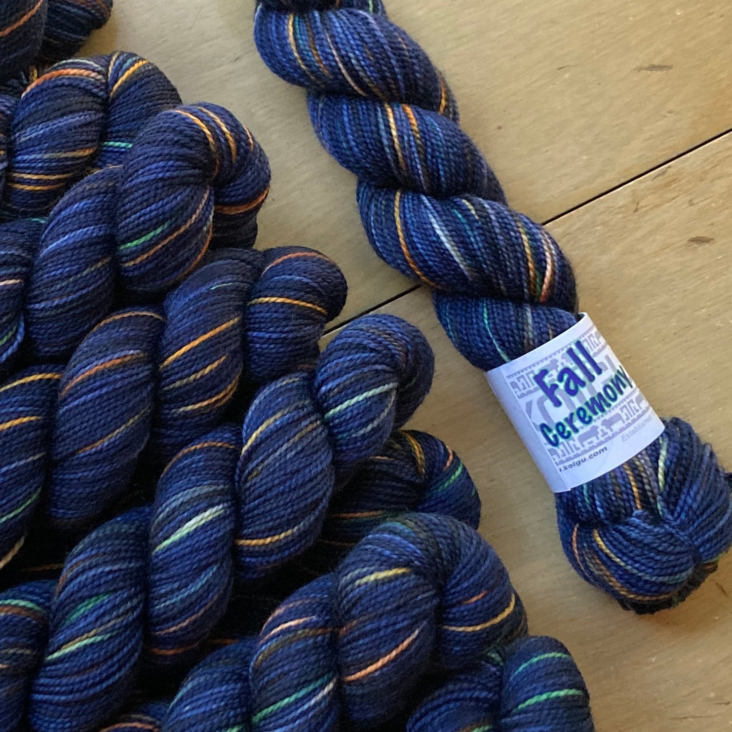 Indigo variegated skeins of Koigu KPPPM yarn arranged on a wooden surface. 