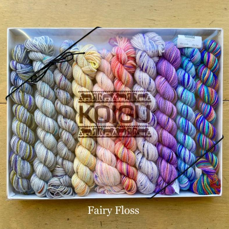 Rectangular package holding ten mini skeins of colorful hand dyed Koigu KPPPM yarn. 
