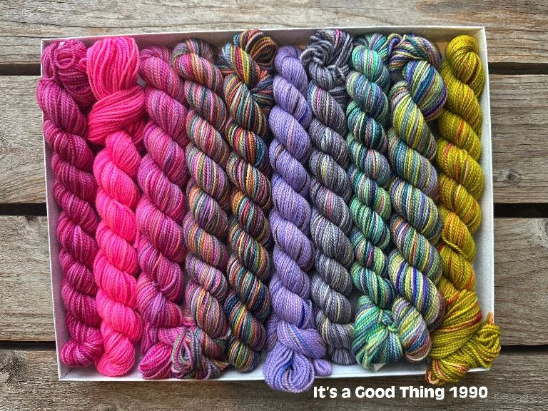 Rectangular package holding ten mini skeins of colorful hand dyed Koigu KPPPM yarn. 