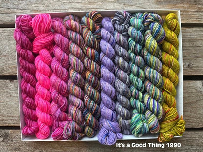 Rectangular package holding ten mini skeins of colorful hand dyed Koigu KPPPM yarn. 