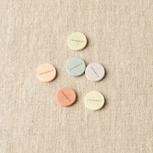 Round pastel magnets on a light gray surface. 