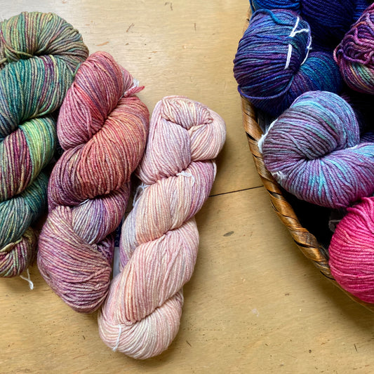 Colorful skeins of Malabrigo Seis Cabos yarn arranged on a wooden surface, for sale at Hillsborough Yarn Shop, NC, USA.